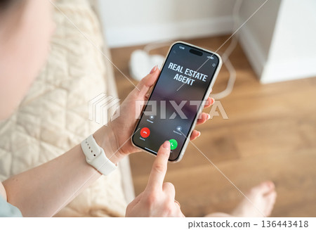 The women receives a call from a real estate agent. Buying an apartment or house. Real estate investments. Young buyer explores market timing and mortgage options for future and smart ownership. 136443418