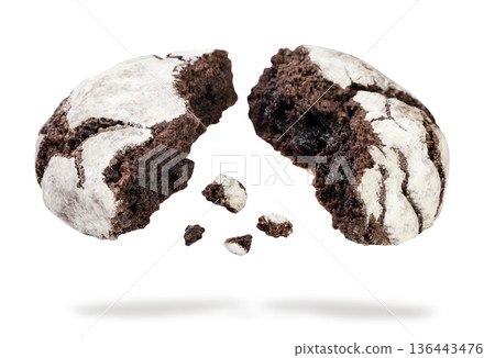 Two halves of chocolate crinkle cookie and crumbs flying on a white background. Isolated Two halves of chocolate crinkle cookie and crumbs flying on a white background. Isolated 136443476