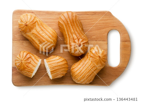 Eclairs and halves on a wooden board on a white background. Top view 136443481