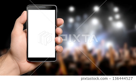 A hand holds a mobile phone displaying a blank screen while people are seen dancing in a night club environment and bright lights A hand holds a mobile phone displaying a blank screen while people are seen dancing in a night club environment and bright lights 136444527