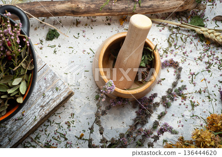 pestle and mortar around dry medicine herbs at white background. top view pestle and mortar around dry medicine herbs at white background. top view 136444620