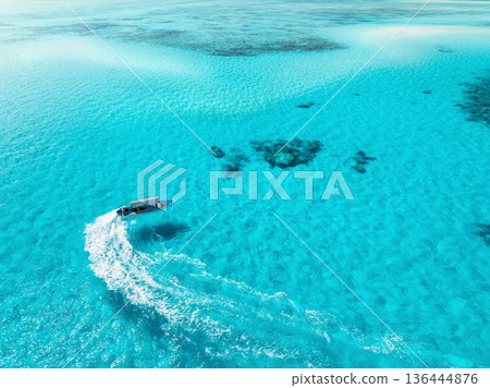 Aerial view of floating boat in clear azure sea in summer Aerial view of floating boat in clear azure sea in summer 136444876