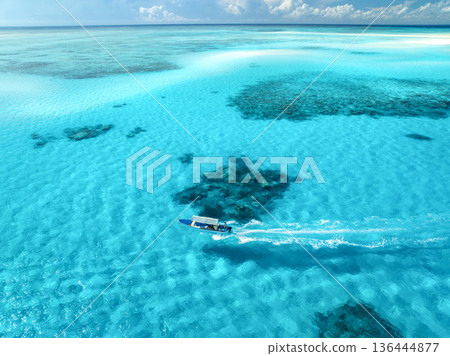 Aerial view of floating boat in clear azure sea in summer Aerial view of floating boat in clear azure sea in summer 136444877
