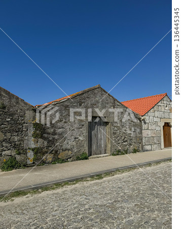 Stone village house along Camino de Santiago route in Portugal with rustic facade and red tile roof. Travel marketing, cultural tourism promotion, slow travel storytelling, destination branding Stone village house along Camino de Santiago route in Portugal with rustic facade and red tile roof. Travel marketing, cultural tourism promotion, slow travel storytelling, destination branding 136445345