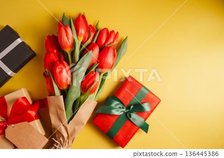 Mothers' day. Red tulips with gift boxes. Easter holiday. Yellow background Mothers' day. Red tulips with gift boxes. Easter holiday. Yellow background 136445386