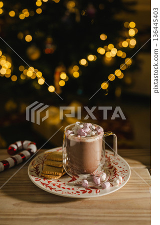 Holiday, Christmas background. A cup with hot chocolate and marshmallows on the table with Christmas tree on background 136445403