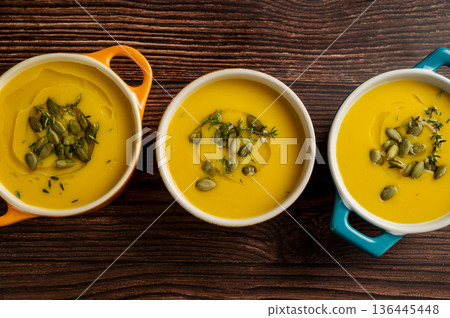 Pumpkin soup in ceramic bowls, wooden background, top view 136445448