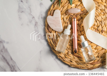 Rose quartz gua sha tool and face massage roller on wooden tray, beauty abstract photo. Top view Rose quartz gua sha tool and face massage roller on wooden tray, beauty abstract photo. Top view 136445481