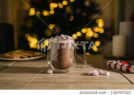 Holiday, Christmas background. A cup with hot chocolate and marshmallows on the table with Christmas tree on background 136445502