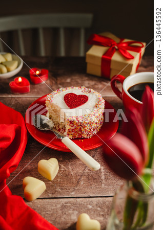 Valentine's Day background. Cake with red heart, candles, gift box and cup of coffee on table. Love celebration Valentine's Day background. Cake with red heart, candles, gift box and cup of coffee on table. Love celebration 136445592