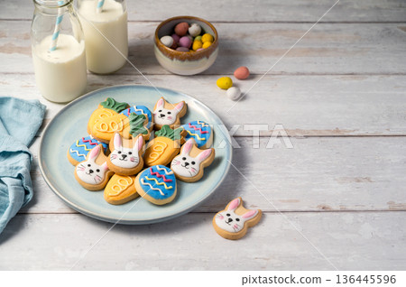 Easter cookies with bottles of milk on white wooden background and mini chocolate easter candy eggs. Spring holidays background 136445596