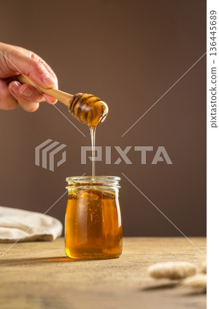 Jar of honey with wooden dipper, sweet liquid, neutral background Jar of honey with wooden dipper, sweet liquid, neutral background 136445689