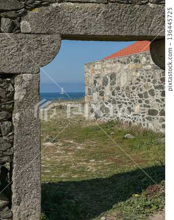 Stone gateway framing coastal landscape near Praia De Paco in Carreco, Caminha, Portugal with traditional masonry, red roof house. Travel, cultural tourism, destination branding and coastal heritage 136445725