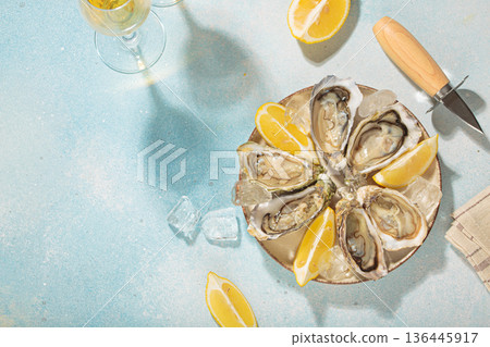 Fresh oysters with lemon and white wine on ice for a luxurious meal on sunny day, blue background, space for text Fresh oysters with lemon and white wine on ice for a luxurious meal on sunny day, blue background, space for text 136445917