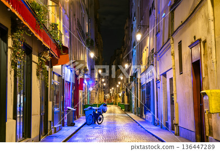 Rue Saint-Sauveur in the 2nd district of Paris France. Historic narrow cobblestone street features illuminated shops and cafes at night 136447289