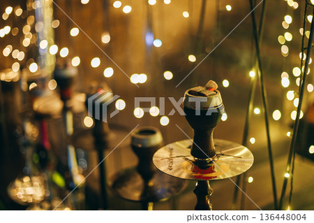 Single Hookah With Glowing Charcoal Against Fairy Light Bokeh Single Hookah With Glowing Charcoal Against Fairy Light Bokeh 136448004