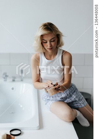 Woman Get Cosmetic Body Scrub From Jar Sitting On Bath In Bathroom 136448008