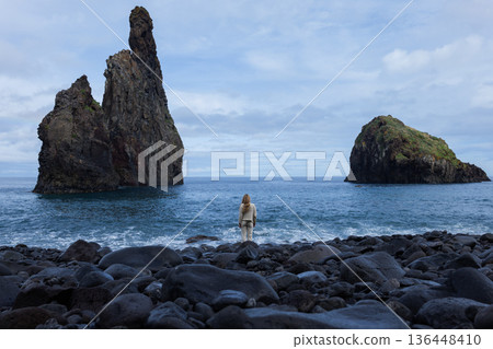 Independent traveler exploring stormy coast under overcast sky 136448410