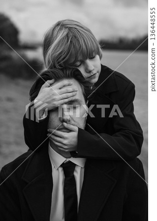 Father and daughter close-up portrait with covering gesture, black and white 136448555