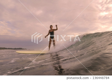 Sunset Glow Silhouettes Woman Skating On Longboard Over Water 136448784