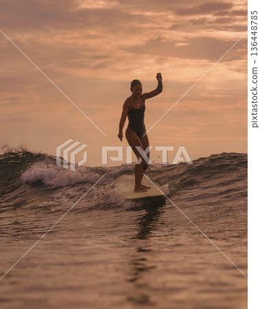 Tranquil Woman Keeps Her Stance On Surfboard By Shoreline At Twilight Tranquil Woman Keeps Her Stance On Surfboard By Shoreline At Twilight 136448785