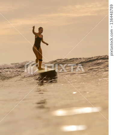 Sunset Glow Silhouettes Woman Skating On Longboard Over Water Sunset Glow Silhouettes Woman Skating On Longboard Over Water 136448789