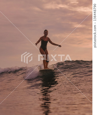 Graceful Female Surfer Maintains Poised Stance During Sunset Surf Graceful Female Surfer Maintains Poised Stance During Sunset Surf 136448790