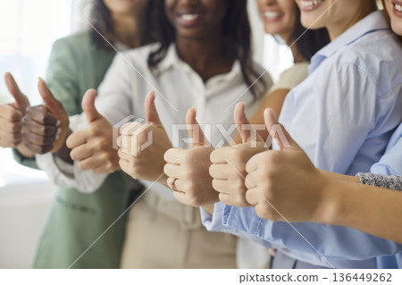 Smiling group of women showing thumbs up, celebrating unity and success together Smiling group of women showing thumbs up, celebrating unity and success together 136449262