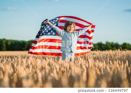 American Little Boy Standing In Golden Wheat Field Holding Usa National Flag American Little Boy Standing In Golden Wheat Field Holding Usa National Flag 136449797
