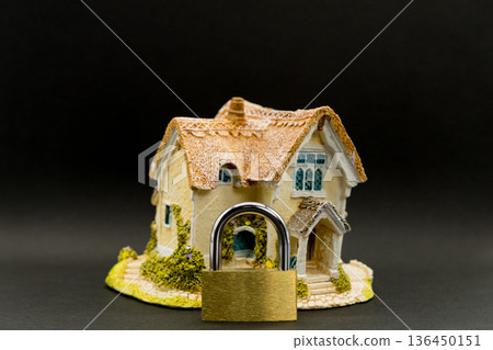 黑色背景上的房屋模型和掛鎖的安全圖像 黑色背景上的房屋模型和掛鎖的安全圖像 136450151