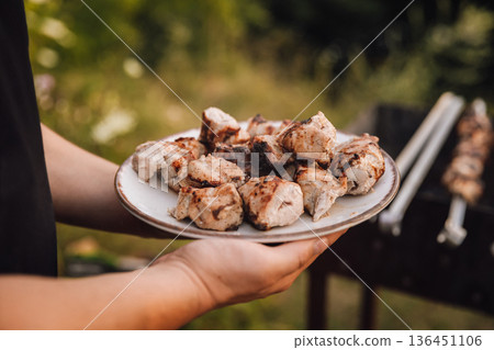 Plate of grilled pork shashlik served outdoors by the barbecue 136451106