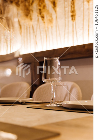 Wine glass on set restaurant table with warm candlelight and pampas decor 136451128