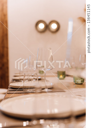 Elegant wine glass on set restaurant table with warm candlelight bokeh Elegant wine glass on set restaurant table with warm candlelight bokeh 136451145