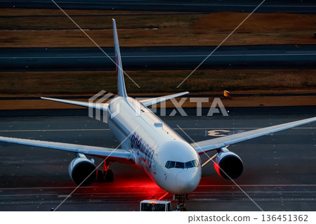 A passenger plane with red lights illuminating the ground A passenger plane with red lights illuminating the ground 136451362