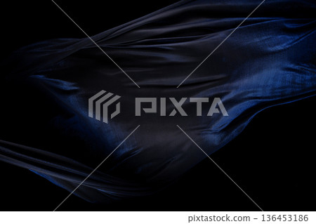 Blue silver shinny fabric flying in curve shape, Piece of textile blue silvery fabric throw fall in air. Black background isolated, dark shading environment 136453186