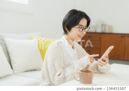 A woman looking at her smartphone in the living room A woman looking at her smartphone in the living room 136453387
