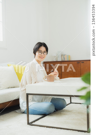 A woman looking at her smartphone in the living room A woman looking at her smartphone in the living room 136453394