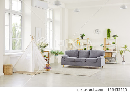 A cozy modern living room interior with a gray sofa and a children's teepee tent 136453513