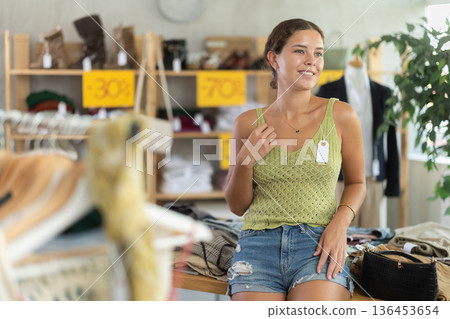 Positive joyful woman looking for fashionable clothes in clothing boutique 136453654