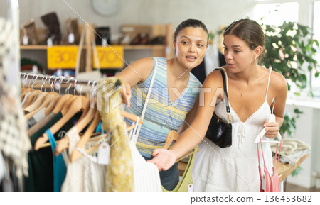 Two joyful women looking for fashionable clothes in clothing boutique 136453682