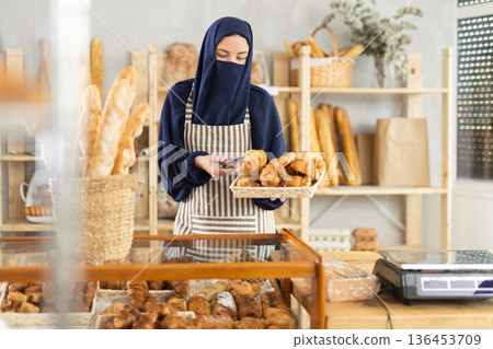 Muslim saleswoman holding a basket of croissants 136453709