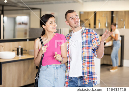 Friendly interracial couple looking for bathroom fixtures in showroom Friendly interracial couple looking for bathroom fixtures in showroom 136453716
