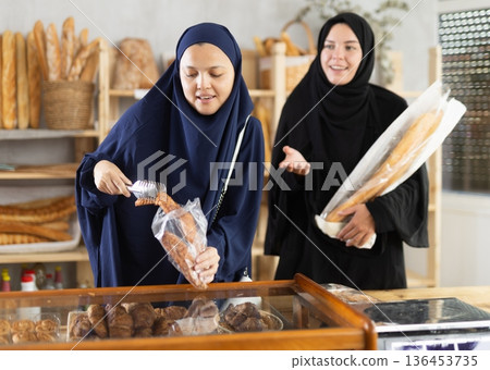 Female shoppers in hijabs selecting baked goods in bakery Female shoppers in hijabs selecting baked goods in bakery 136453735