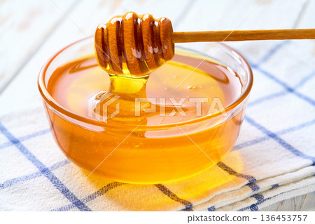 Natural honey in a glass bowl on a light kitchen table, selective focus. Natural honey in a glass bowl on a light kitchen table, selective focus. 136453757