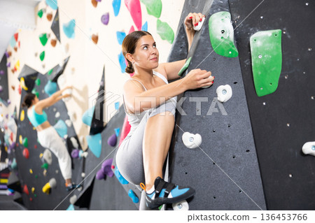Young woman practicing rock climbing on climbing wall Young woman practicing rock climbing on climbing wall 136453766