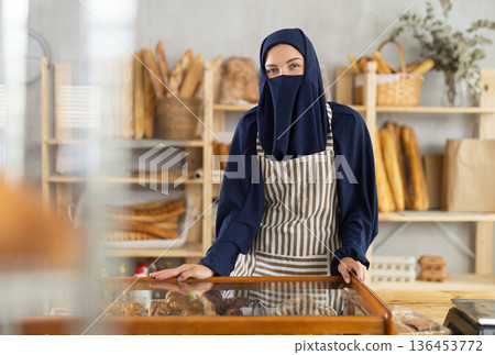 Polite Muslim female bakery owner welcoming customers Polite Muslim female bakery owner welcoming customers 136453772