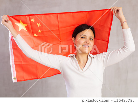 Joyful female fan of the favorite team of China with national flag in her hands Joyful female fan of the favorite team of China with national flag in her hands 136453783