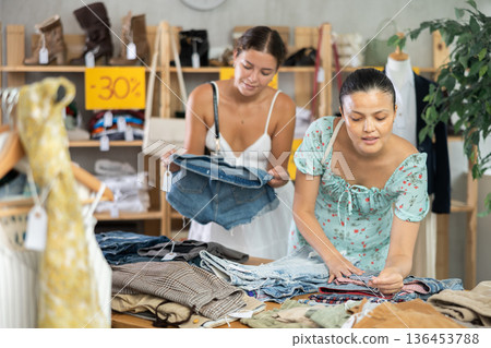 Women customers turn over and choose trousers or shorts in store Women customers turn over and choose trousers or shorts in store 136453788