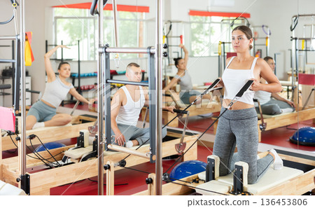 Young girl doing arm exercises on cable reformer device Young girl doing arm exercises on cable reformer device 136453806