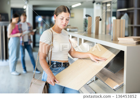 Young woman choosing laminate floorboards in home improvement store Young woman choosing laminate floorboards in home improvement store 136453852
